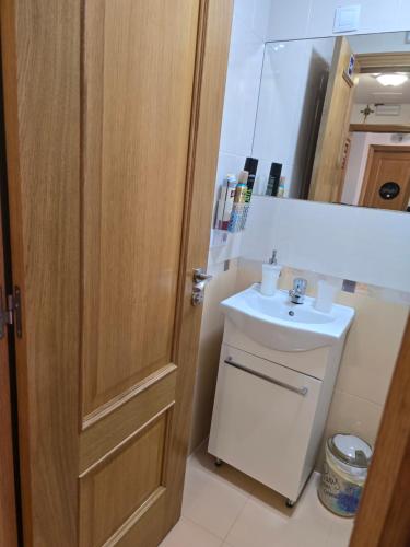 a bathroom with a sink and a wooden door at Pension Myriam O PEDROUZO in O Pedrouzo