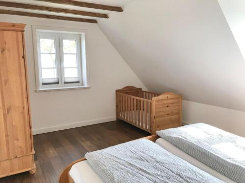 a attic bedroom with two beds and a crib at Deichhof-Knudsen in Oldsum