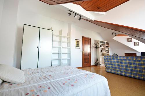 a bedroom with a large bed and a blue chair at Enorme TRIPLEX en el centro de O Grove in O Grove