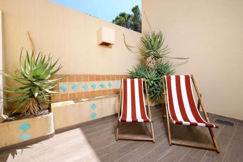 two red and white striped chairs sitting next to plants at Le Saint Erasme, Hotel Eco Friendly in Calvi