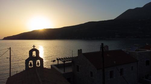 a church with the sun setting over the water at Sun Villa in Neon Oitilon