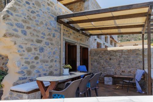 a patio with a table and chairs and a stone wall at Sun Villa in Neon Oitilon