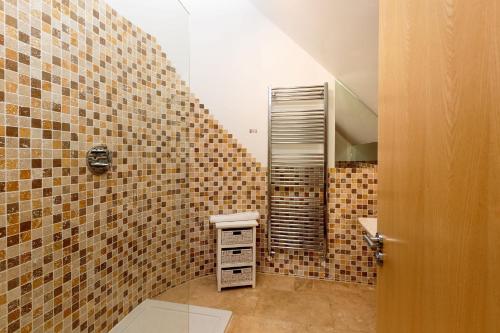 a bathroom with tiled walls and a toilet in a room at Luxurious 4 Bedroom New England Style Villa - Trewhiddle Villa 23 in St Austell