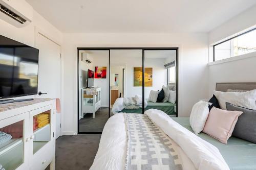 a bedroom with a bed and a living room at Stunning, modern, two-story detached townhouse in Melbourne