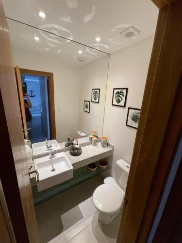 a bathroom with a sink and a toilet and a mirror at Imperia Lounge Itacimirim in Camacari