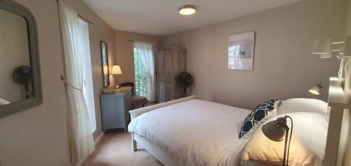 une chambre avec un lit blanc et une fenêtre dans l'établissement La Maison du Tourniquet, à Aubeterre-sur-Dronne