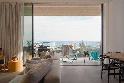 a living room with a couch and a large window at Protaras Eden Seaside Suite in Protaras