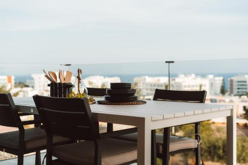 a dining room table with chairs and a view of the city at Protaras Eden Seaside Suite in Protaras