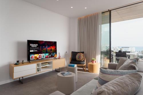 a living room with a flat screen tv on a cabinet at Protaras Eden Seaside Suite in Protaras