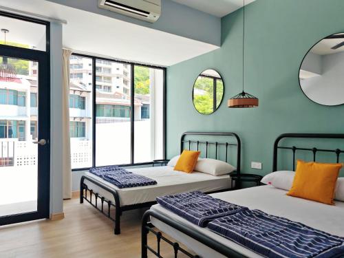 two beds in a room with blue walls and windows at 35 BeachHouse Batu Ferringhi 7 Bedroom 7 Bathroom EV friendly in Batu Ferringhi