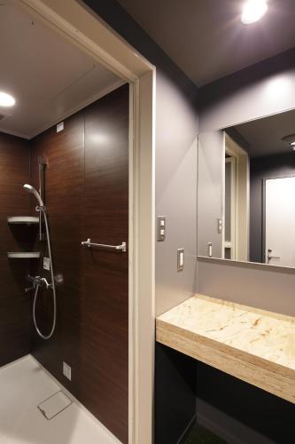 a bathroom with a shower and a large mirror at Booth Netcafe & Capsule in Tokyo