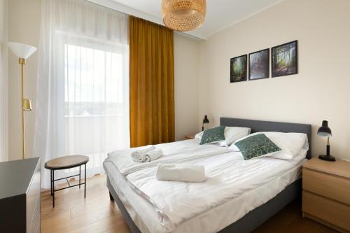 a bedroom with a large white bed and a window at Apartament Miodowy - Penthouse z balkonem in Kudowa-Zdrój