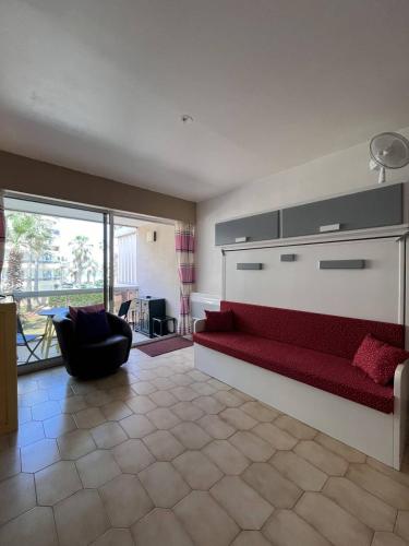 - un salon avec un canapé rouge et une chaise dans l'établissement Charmant studio à 20 m de la plage - 2BEAZUR99, à Canet