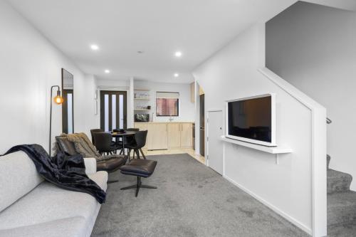 a living room with a couch and a television at Stylish and Sleek City Stay in Christchurch