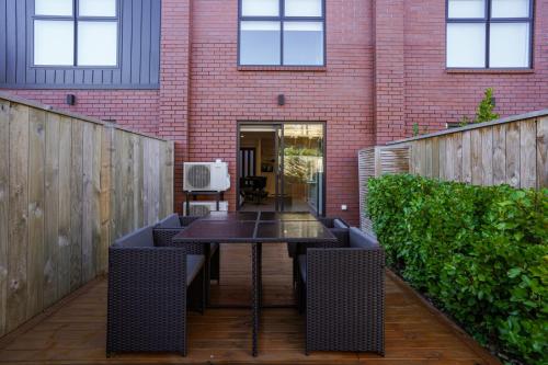 a patio with a table and chairs and a brick building at Stylish and Sleek City Stay in Christchurch