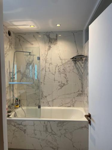 une salle de bain avec douche et baignoire avec un mur en marbre dans l'établissement Superbe appartement refait avec terrasse, à Neuilly-sur-Seine