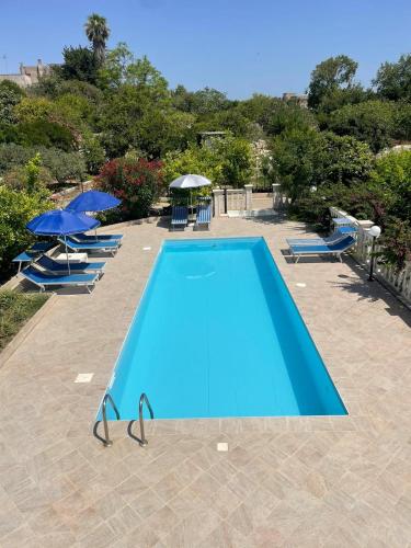 an empty swimming pool with chairs and umbrellas at CASA PAPADIA in Uggiano la Chiesa