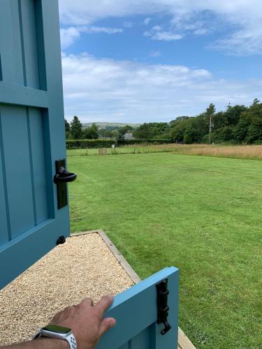 a person opening a door to a field of grass at St. Kew Shepherd Huts in Wadebridge