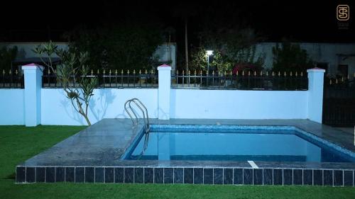 a swimming pool at night with a bench next to a fence at Thai Stays Villa in Shenwa