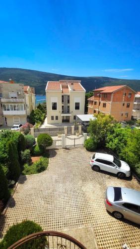two cars parked in a parking lot in front of a house at Sunny Portside Apartment in Ðenovići