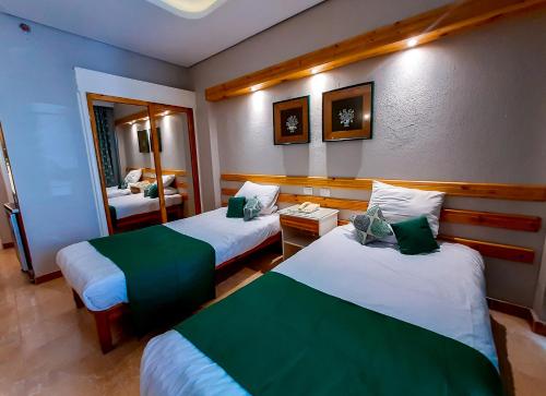 a hotel room with two beds and a mirror at Beau Site Hotel in Marsa Matruh