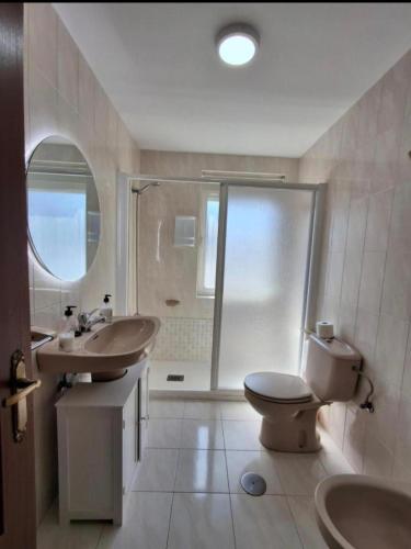 a bathroom with a toilet and two sinks and a shower at Apartamento Arriondas in Arriondas