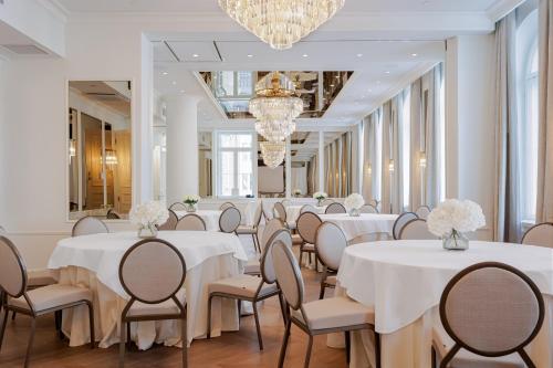 a room with white tables and chairs and a chandelier at The Hotel Maria Helsinki in Helsinki