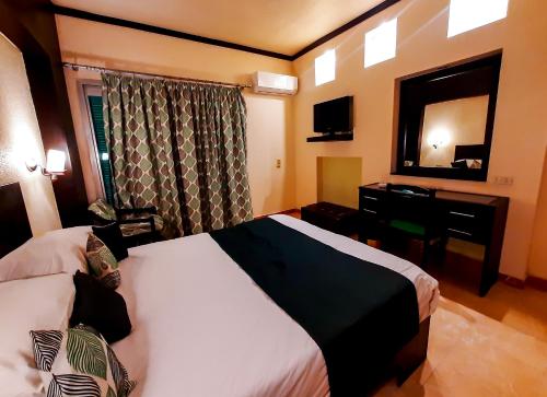 a hotel room with a bed and a desk and a mirror at Beau Site Hotel in Marsa Matruh