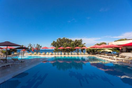 a large swimming pool with umbrellas and chairs at Family Hotel La Luna - All inclusive in Lun
