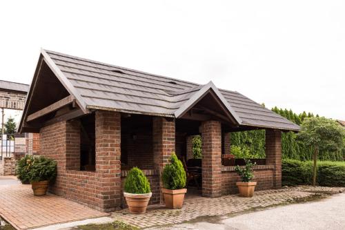 a brick building with a black roof and potted plants at Penzión Pri Mlyne in Nitra
