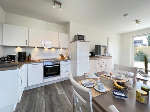 a kitchen with white cabinets and a wooden table at ZUR STEILKÜSTE Wellness-Appartement APPARTO Grömitz in Grömitz
