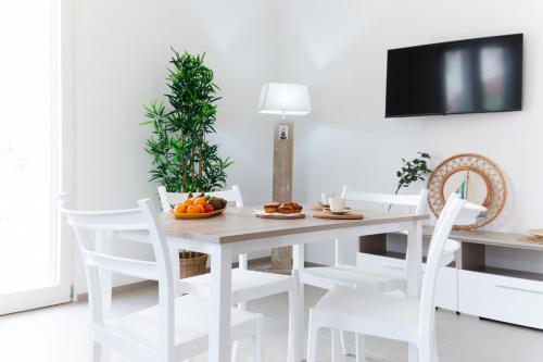a white dining room with a white table and white chairs at Goccia Celeste - Gocce sul Mare in Savelletri di Fasano