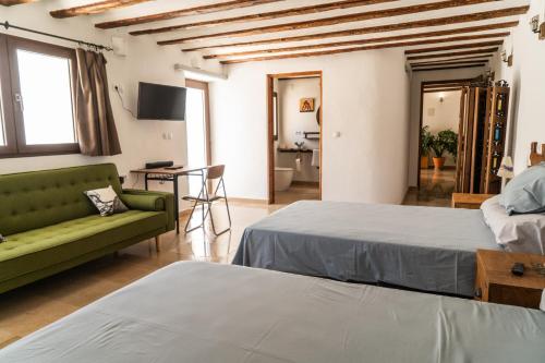 a bedroom with two beds and a green couch at Cortijo Los Llanos in Huéscar