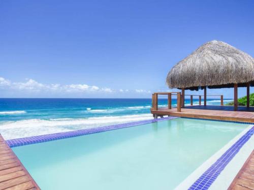 a swimming pool with a gazebo and the ocean at Aloha 1 in Ponta Mamoli