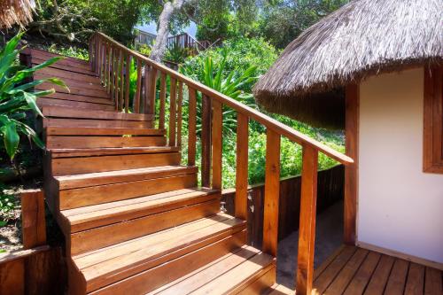 a wooden staircase leading to a hut with a thatch roof at Aloha 1 in Ponta Mamoli