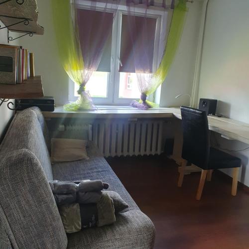 a living room with a couch and a desk and a window at Stara Szkoła Jedwabno in Jedwabno