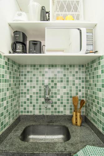 a sink in a kitchen with green tiles at Studio 202 in Petrópolis