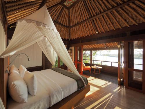 1 dormitorio con 1 cama con mosquitera en The Menjangan by LifestyleRetreats, en Banyuwedang