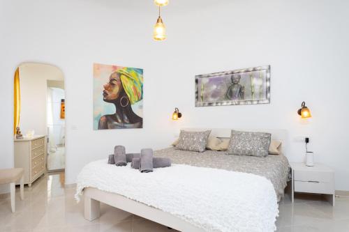 a white bedroom with a bed and a painting on the wall at Atlantic Dream with pool and jacuzzi Only Adults in Puerto de Santiago