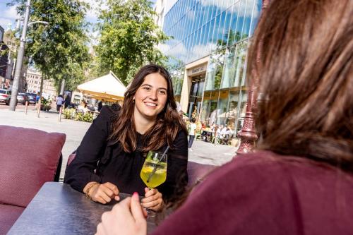 a woman sitting at a table with a glass of wine at Mister Highland Hotel in Amsterdam