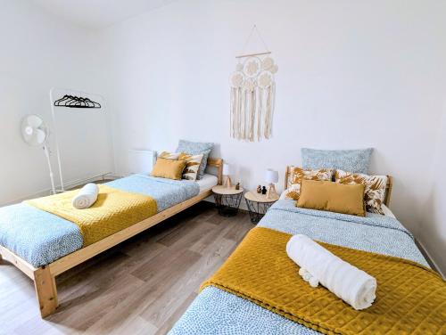 - 2 lits dans une chambre de couleur bleue et jaune dans l'établissement L'escapade des poètes - central - baby-foot, à Béziers