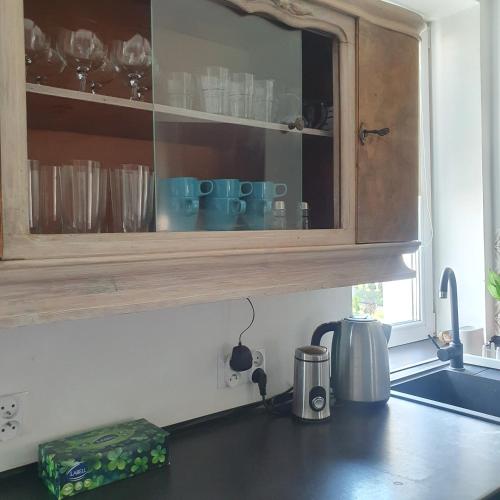 a kitchen counter with a cupboard with glasses in it at Stara Szkoła Jedwabno in Jedwabno