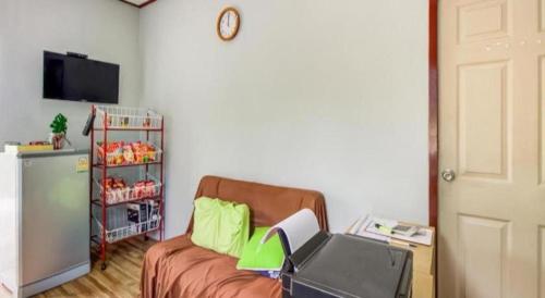 salon z kanapą i zegarem na ścianie w obiekcie Baan Siripaka w mieście Prachuap Khiri Khan