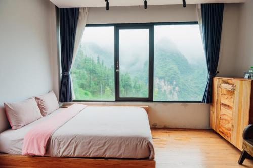 a bedroom with a bed and a large window at Đồng Văn Golden Hotel in Dồng Văn