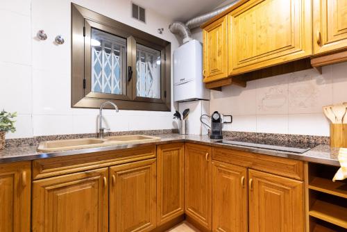 a kitchen with wooden cabinets and a sink at UHC SANTILLANA FAMILY COMPLEX in Salou