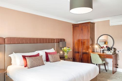 a bedroom with a large bed with a desk and a chair at The Kingsley Hotel in Cork