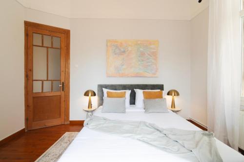 a bedroom with a large white bed with two lamps at Majestic Villa overlooking Acropolis with Hot Tub in Athens