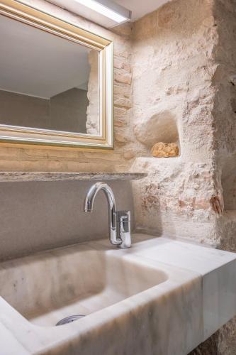 a bathroom sink with a mirror and a stone wall at Majestic Villa overlooking Acropolis with Hot Tub in Athens