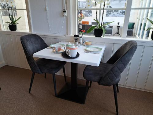 a table with two chairs and a white table with dishes on it at Hotel Het Gouden Boltje in De Koog