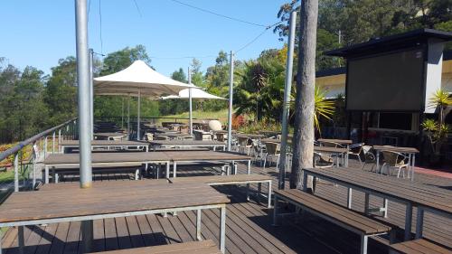 
a patio area with tables, chairs and umbrellas at Wisemans Inn in Wisemans Ferry
